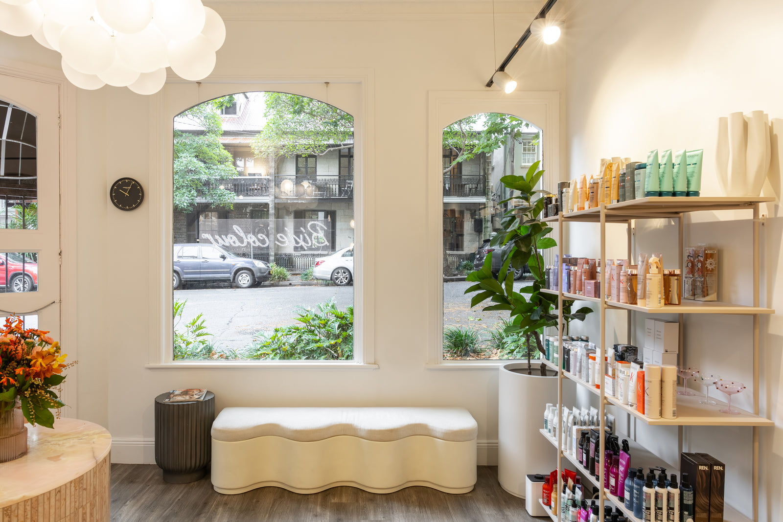 Modern salon interior of a store with shelves, bench, and large windows.