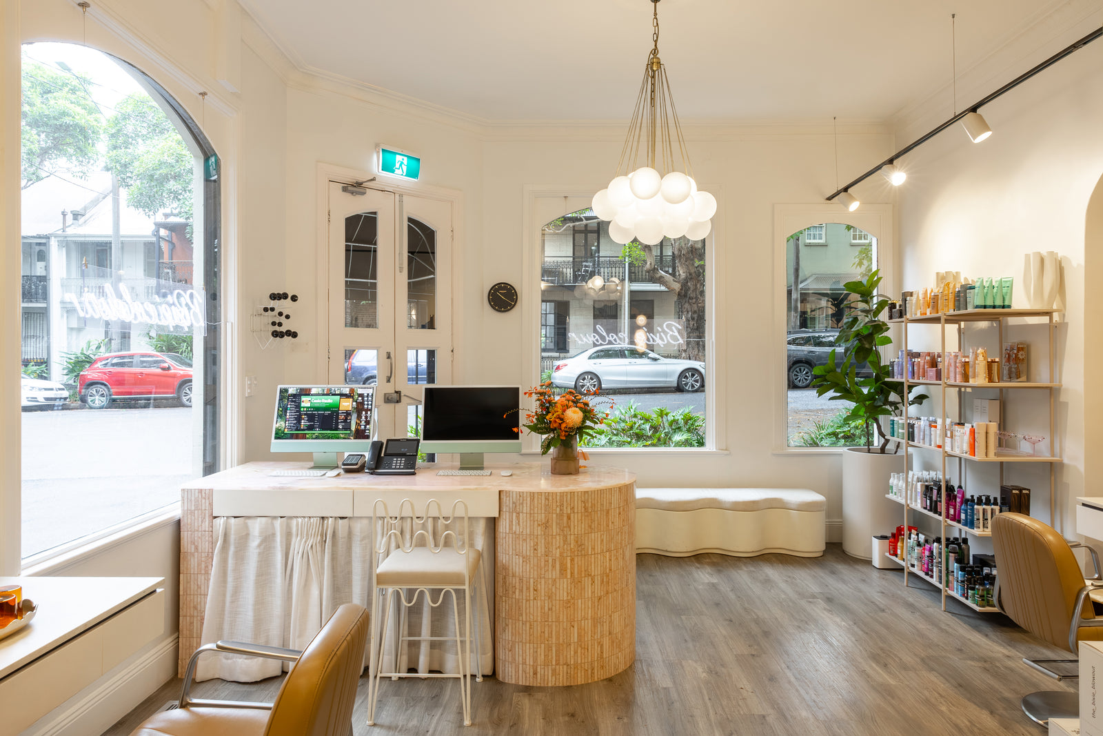 Modern interior salon space with a reception desk, chairs, and shelves.