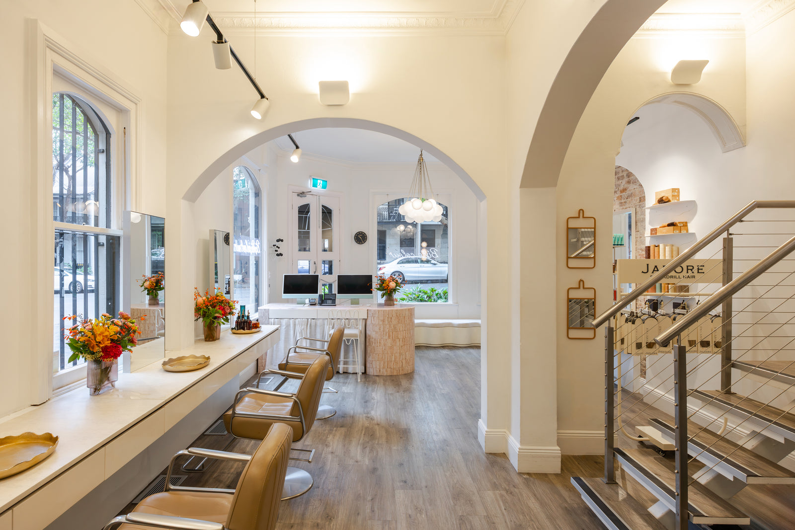 Modern salon interior with a counter, chairs, and a staircase.