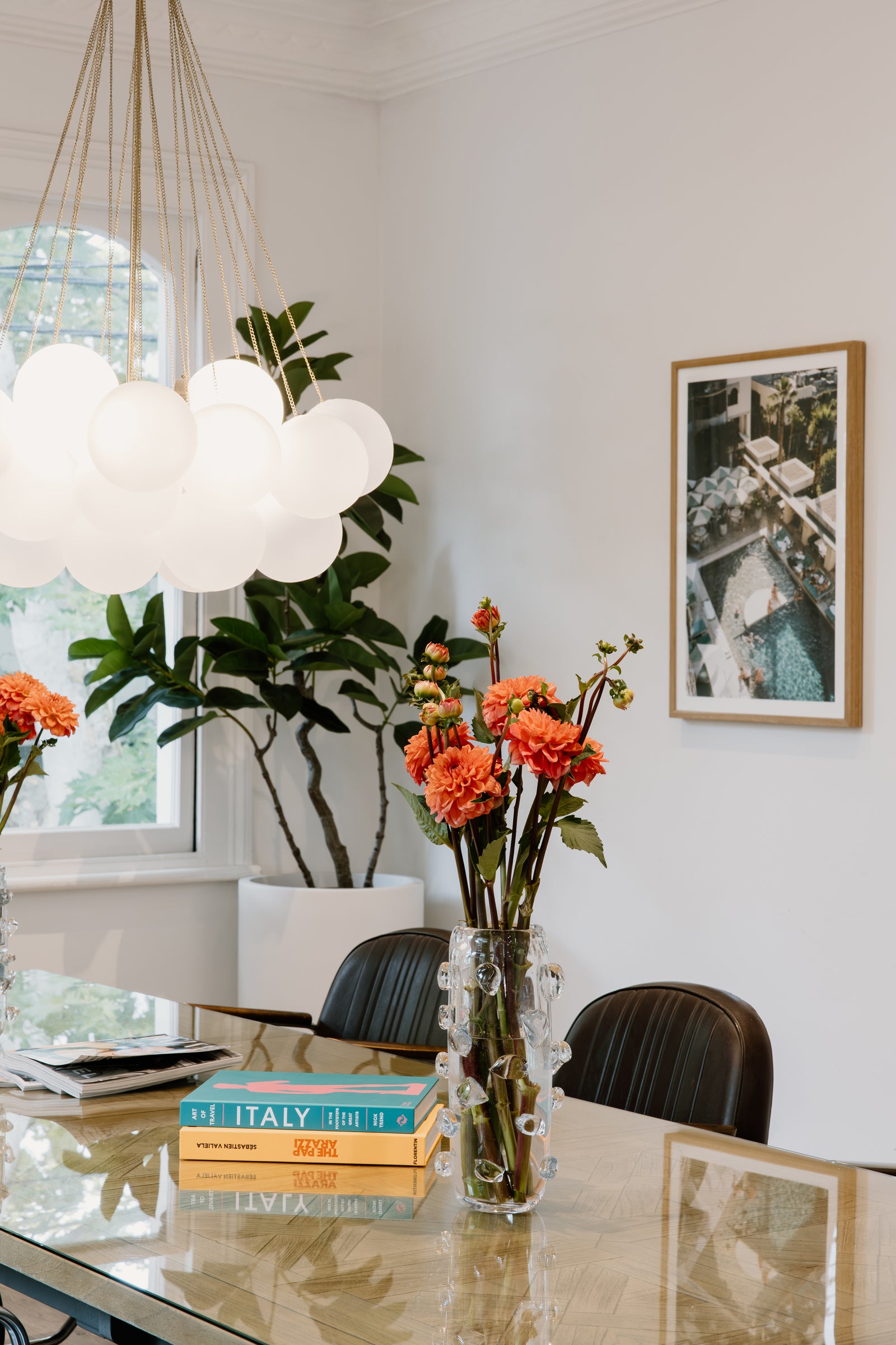 Modern salon interior with a table, books, flowers, and a plant.