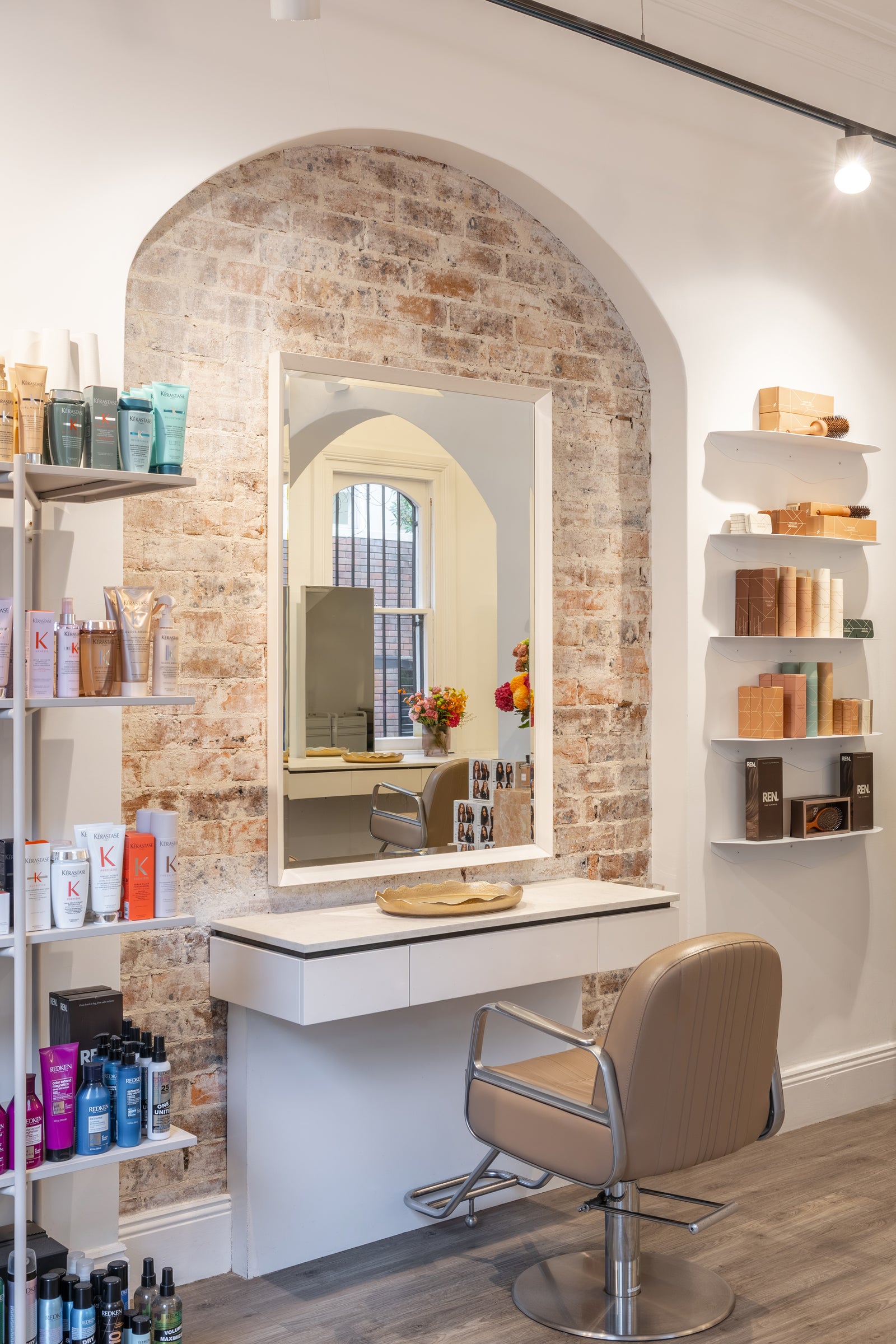 Salon interior with a mirror, chair, and shelves with products.