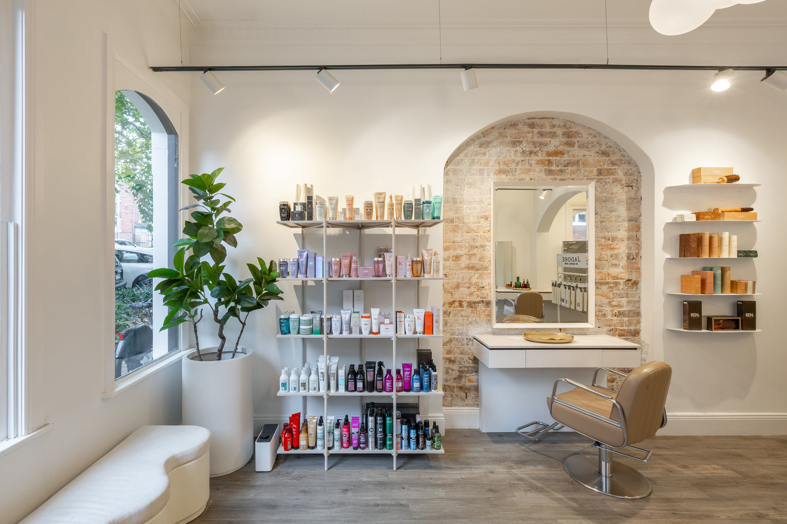 Modern hair salon interior with shelves, mirror, and chair.