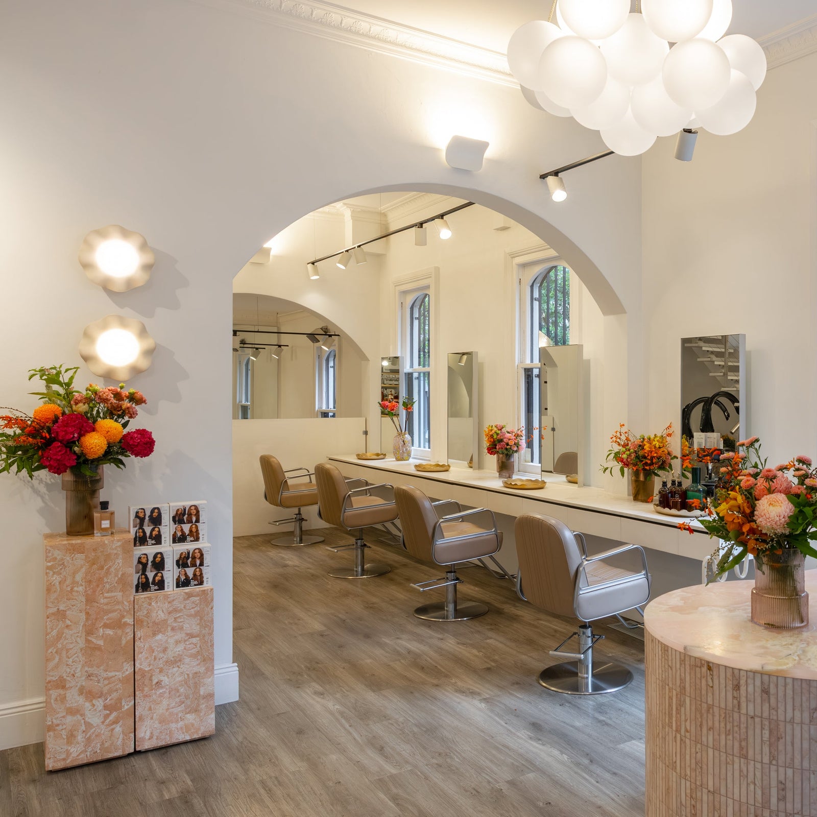 Modern hair salon interior with reception desk, chairs, mirrors and decorative elements.