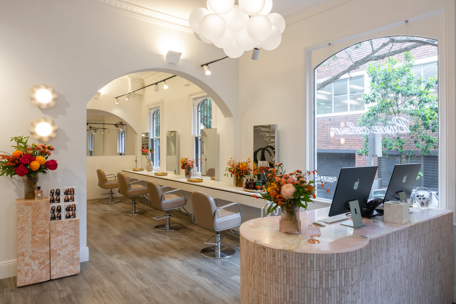 Modern salon interior with reception desk, chairs, mirrors and decorative elements.